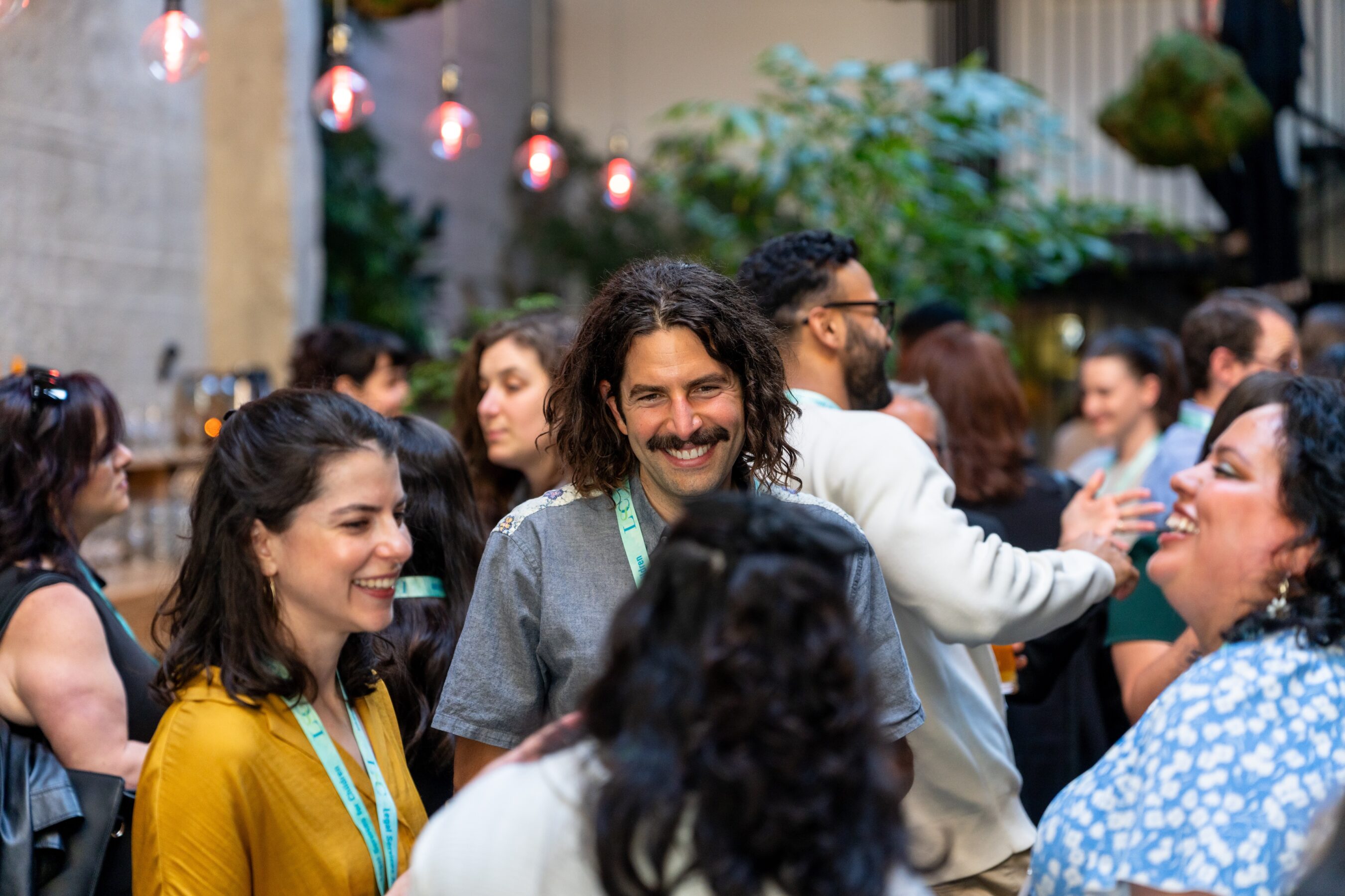 A group of event attendees stand together chatting and laughing