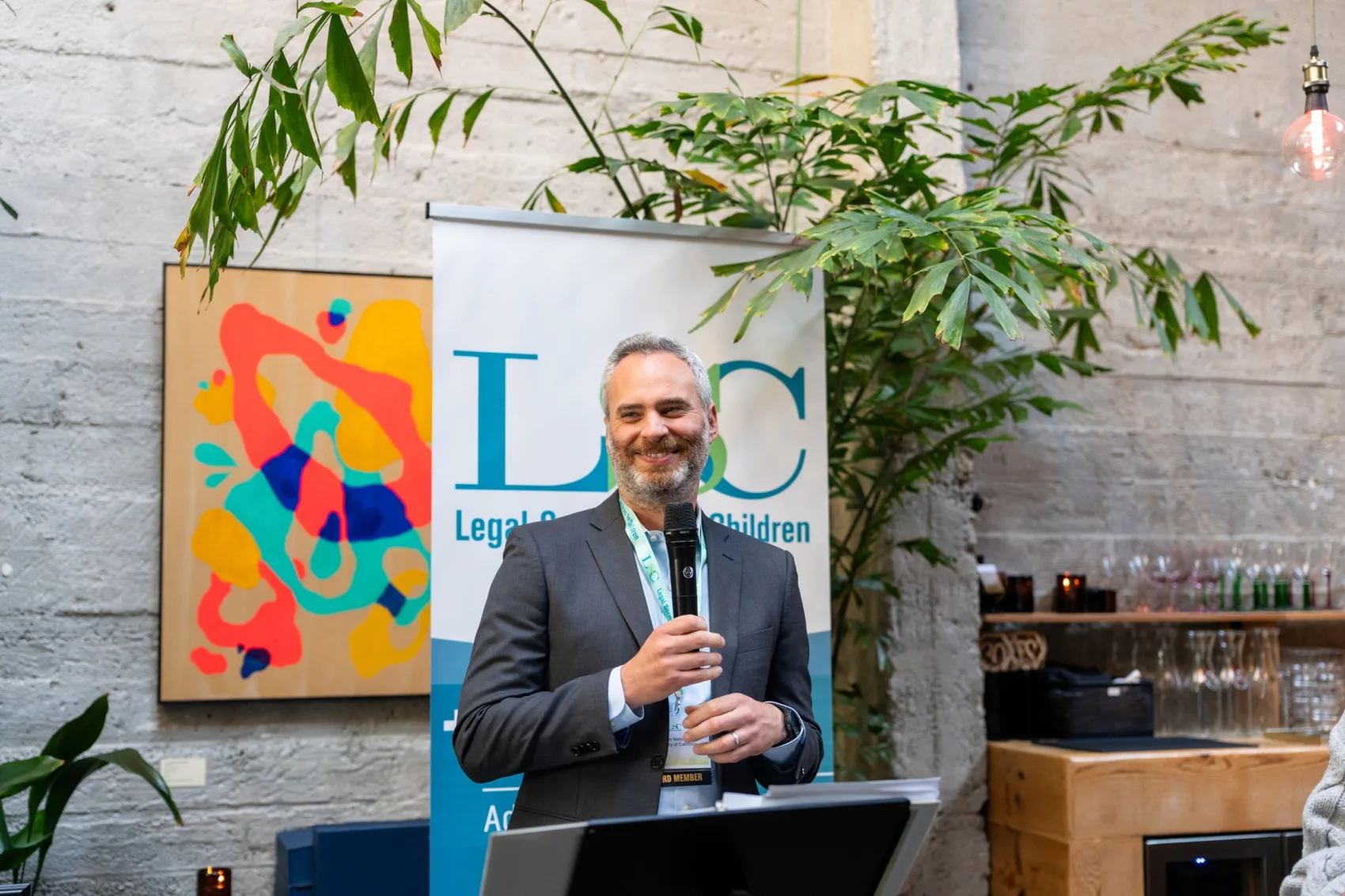 LSC board member Josh Meltzer holding a microphone and addressing event attendees
