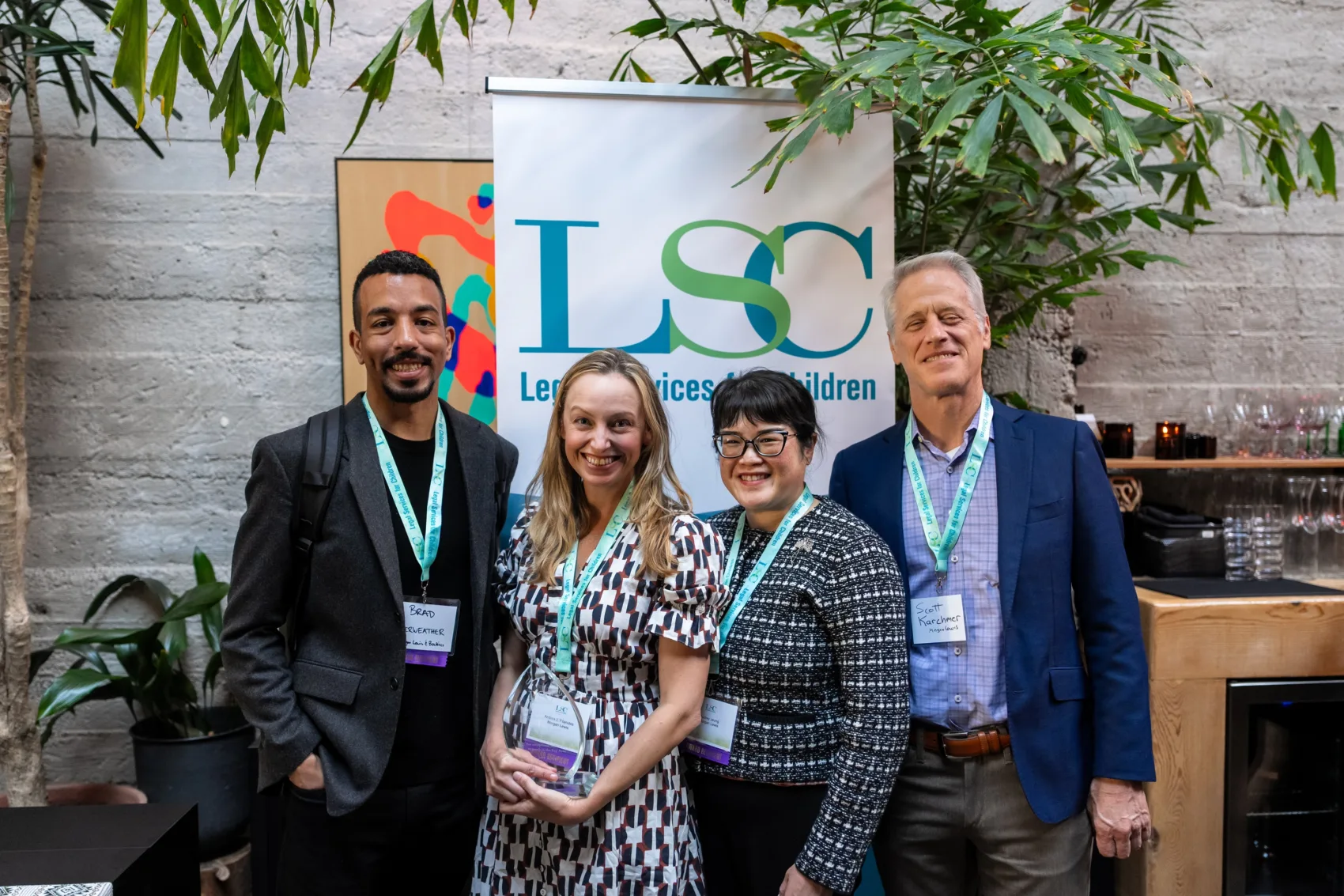 Four LSC Excellence in Pro Bono awardees, including LSC board member Scott Karchmer, standing in front of an LSC banner