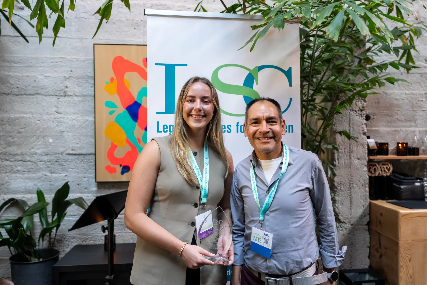 An LSC awardee standing with LSC Clinical Director Ron Gutierrez in front of an LSC banner